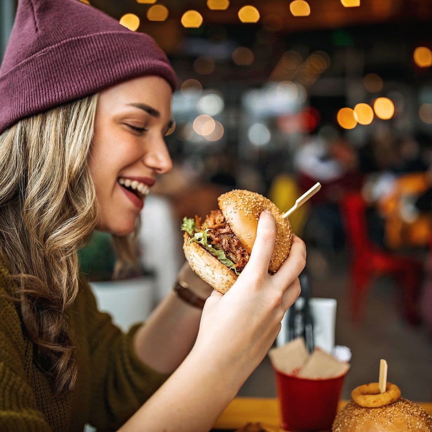 Une femme mangeant un burger.