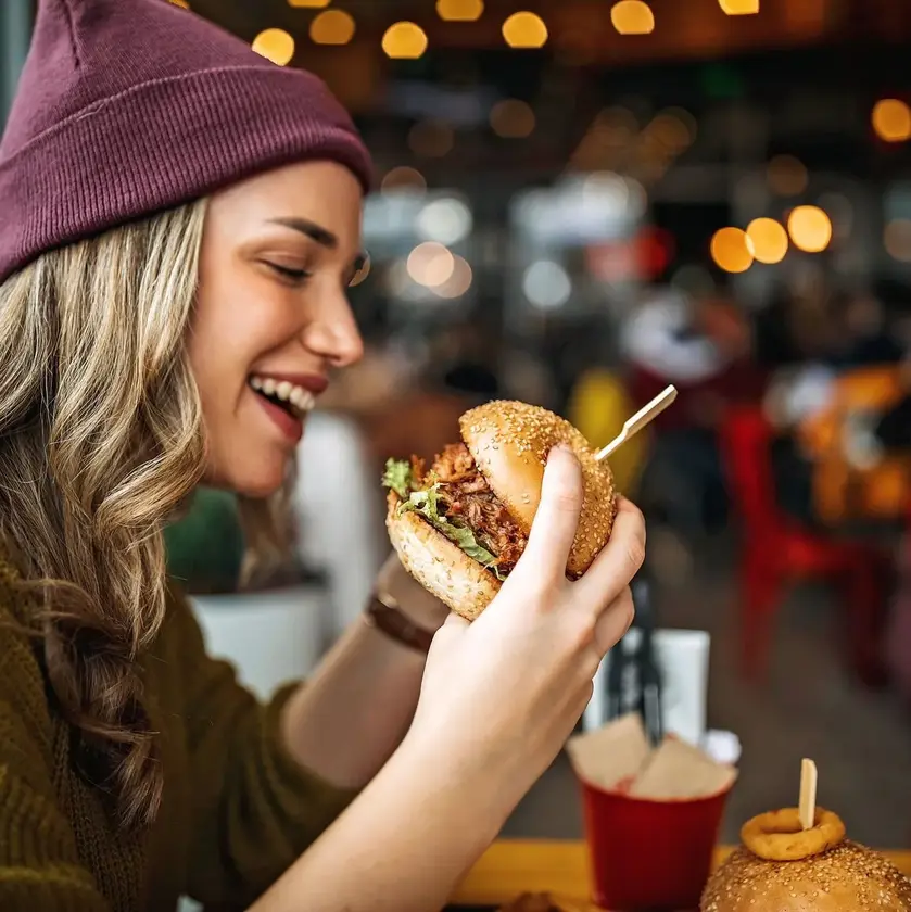 Cliente appréciant un burger commandé via Circlee Une cliente mangeant un burger